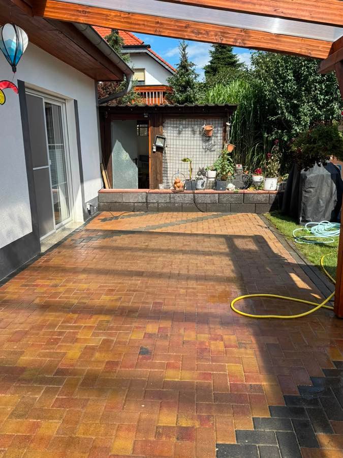 Dieselbe Terrasse nach der Reinigung: das Pflaster ist gleichmäßig hell und die Steinfarbe wieder sichtbar.